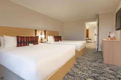 a hotel room with two beds and a television at Executive Suites Hotel & Conference Center, Metro Vancouver in Burnaby