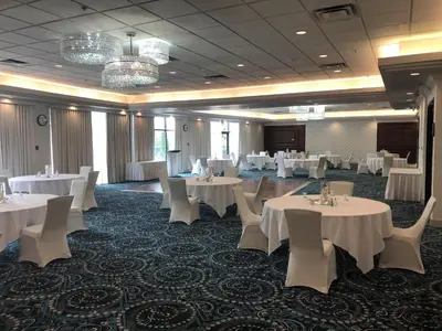 a banquet room with white tables and white chairs at Executive Suites Hotel & Conference Center, Metro Vancouver in Burnaby