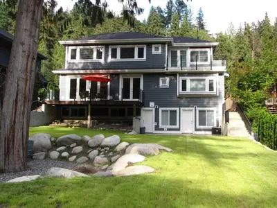 a large house with a lawn in front of it at Riverfront Bed and Breakfast in North Vancouver