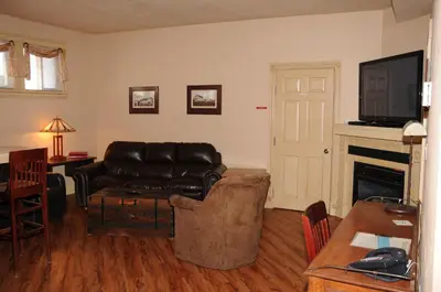 a living room with a leather couch and a fireplace at Third Mission Heritage Suites in Peace River