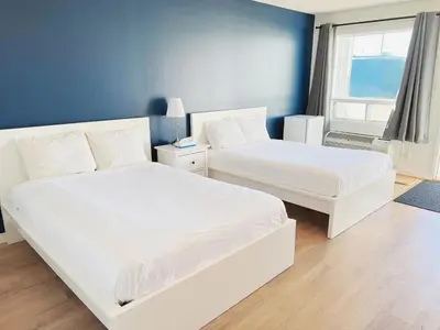 a bedroom with two beds and a blue wall at Riverside Inn in Wabasca
