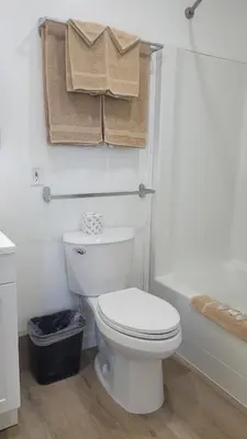 a white bathroom with a toilet and a bath tub at Riverside Inn in Wabasca