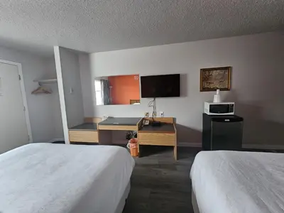 a hotel room with two beds and a desk at Howard Johnson by Wyndham Edson in Edson