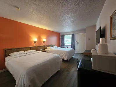 two beds in a hotel room with orange walls at Howard Johnson by Wyndham Edson in Edson