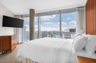 a bedroom with a large white bed and a large window at Embarc Vancouver in Vancouver