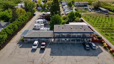an aerial view of a house with cars parked in a parking lot at Maple Leaf Motel & RV Park Resort in Oliver