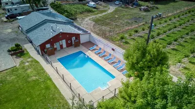 an overhead view of a swimming pool with chairs and a house at Maple Leaf Motel & RV Park Resort in Oliver