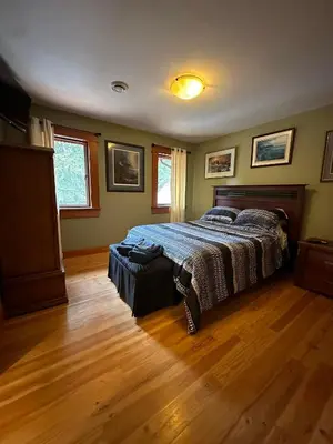 a bedroom with a bed and a wooden floor at Paradise Acres Ranch in Nanoose Bay