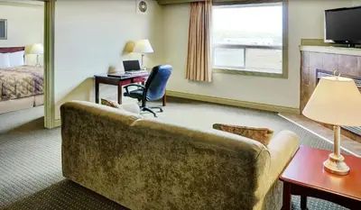 a hotel room with a couch and a desk and a bed at Nova Inn Peace River in Peace River