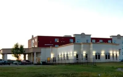 a large white building with lights in a field at Nova Inn Peace River in Peace River