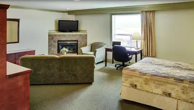 a hotel room with a bed and a fireplace at Nova Inn Peace River in Peace River