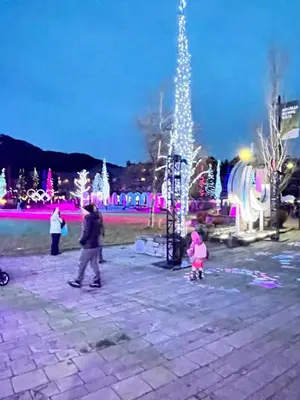 a woman and a child walking in a park with christmas lights at Mountainview 1 bedroom suite with check in services king size bed walk to Village WIFI cable TV free parking boot and glove warmer in Pemberton