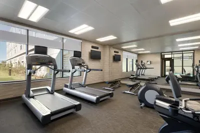 a gym with several treadmills and elliptical machines at Hotel Dene & Conference Centre in Cold Lake