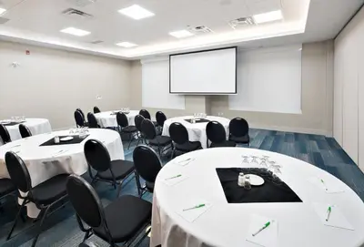 a conference room with white tables and chairs and a screen at Holiday Inn Express - Red Deer North by IHG in Red Deer