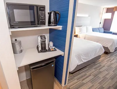a hotel room with a microwave and a bed and a room at Holiday Inn Express - Red Deer North by IHG in Red Deer