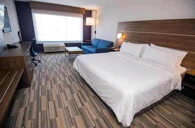 a hotel room with a large bed and a blue chair at Holiday Inn Express - Red Deer North by IHG in Red Deer