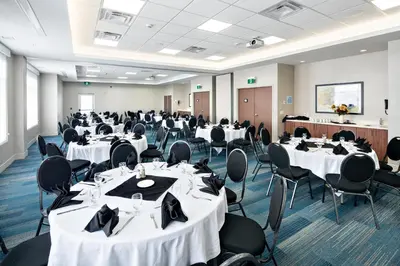 a banquet hall with white tables and black chairs at Holiday Inn Express - Red Deer North by IHG in Red Deer