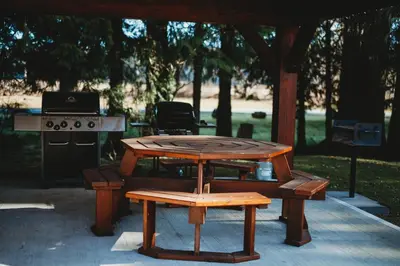 a picnic table with a grill and a table with a bench at Port Hardy Cabins in Port Hardy