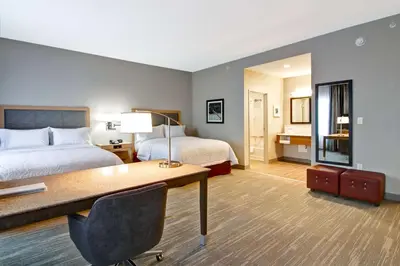 a hotel room with two beds and a desk at Hampton Inn & Suites by Hilton Grande Prairie in Grande Prairie