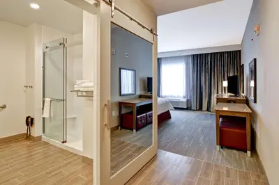 a hotel room with a shower and a bedroom at Hampton Inn & Suites by Hilton Grande Prairie in Grande Prairie