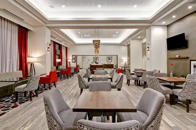 a waiting room with tables and chairs and a tv at Hampton Inn & Suites by Hilton Grande Prairie in Grande Prairie