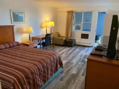 a hotel room with a bed and a desk at Raven Motor Inn in High Prairie