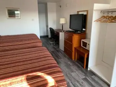 a hotel room with a bed and a flat screen tv at Raven Motor Inn in High Prairie