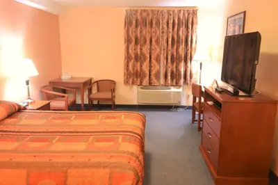 a hotel room with a bed and a flat screen tv at Aurora Park Inn & Suites in Dawson Creek