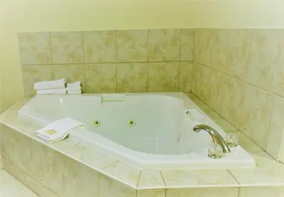 a bathroom with a bath tub with a sink at Aurora Park Inn & Suites in Dawson Creek