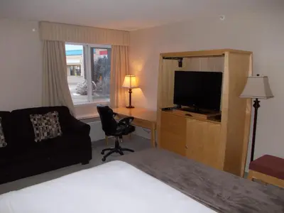 a hotel room with a bed and a desk with a television at Rocky Inn Express in Rocky Mountain House