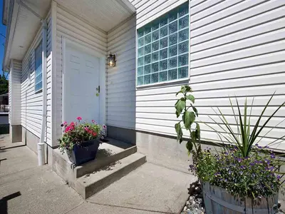 a white house with potted plants and a door at Marpole Guest House in Vancouver