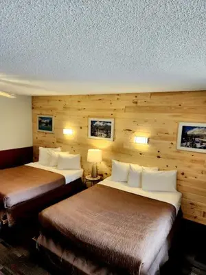 two beds in a hotel room with wooden walls at Rundle Mountain Lodge in Canmore