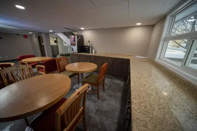 a restaurant with wooden tables and chairs and a counter at Northern Lights Inn in Fort Saint John