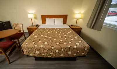 a bedroom with a bed and a table and two lamps at Northern Lights Inn in Fort Saint John
