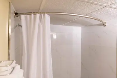 a shower with a white shower curtain in a bathroom at Northern Lights Inn in Fort Saint John