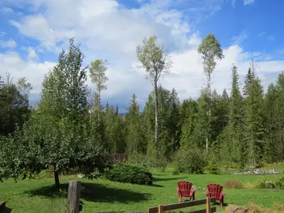 two red chairs in a field with trees at Cedar Haven Cabins and Resort in Clearwater