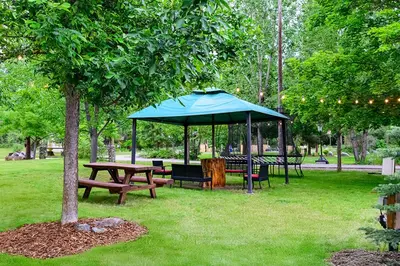 a picnic table and a blue umbrella in a park at Barefoot Villas and Retreat in Christina Lake