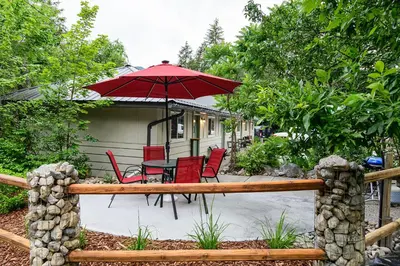 a patio with a table and chairs and an umbrella at Barefoot Villas and Retreat in Christina Lake