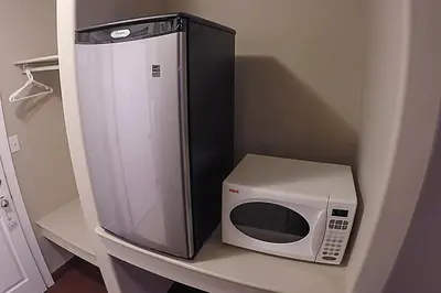 a microwave sitting on a shelf next to a refrigerator at Westwood Inn in Drayton Valley