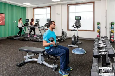 a man sitting on a chair in a gym at Holiday Inn Express & Suites - West Edmonton-Mall Area by IHG in Edmonton
