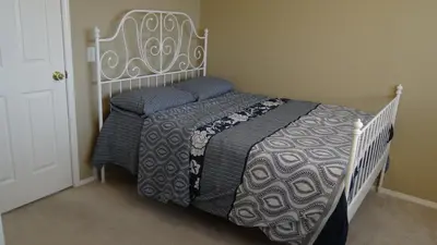 a bedroom with a white bed with blue pillows at Brother Li Homestay in Calgary
