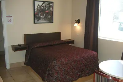 a bedroom with a bed with a red comforter and a window at Trailside Inn in Lloydminster