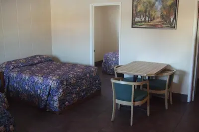 a room with a bed and a table and a bed and a desk at Trailside Inn in Lloydminster