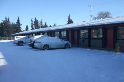 two cars parked outside of a building in the snow at Trailside Inn in Lloydminster