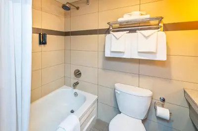 a bathroom with a tub and a toilet and towels at Banff Inn in Banff