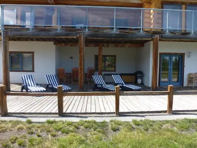 a deck with blue and white chairs on a house at Little Black Bear Lodge/B&B in Bridge Lake