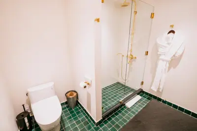 a bathroom with a toilet and a green tiled floor at Eleven Revelstoke Lodge in Revelstoke