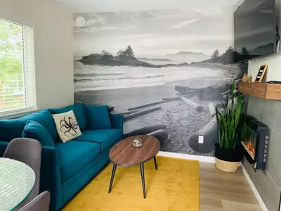 a living room with a blue couch and a beach mural at The Francis Boutique Inn in Ucluelet
