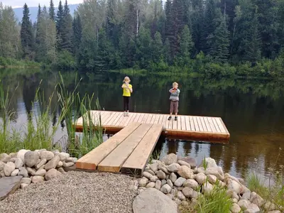 two girls standing on a dock in a lake at Wolfwood Guest Ranch in Clearwater