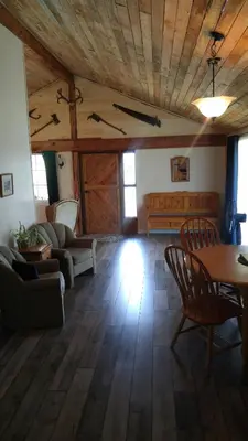 a living room with a wooden ceiling and a table and chairs at Wolfwood Guest Ranch in Clearwater